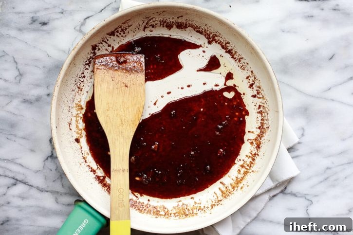 A ginger soy sauce glaze gently simmers in a frying pan, thickening to a perfect consistency, ready to coat the crispy baked tofu.