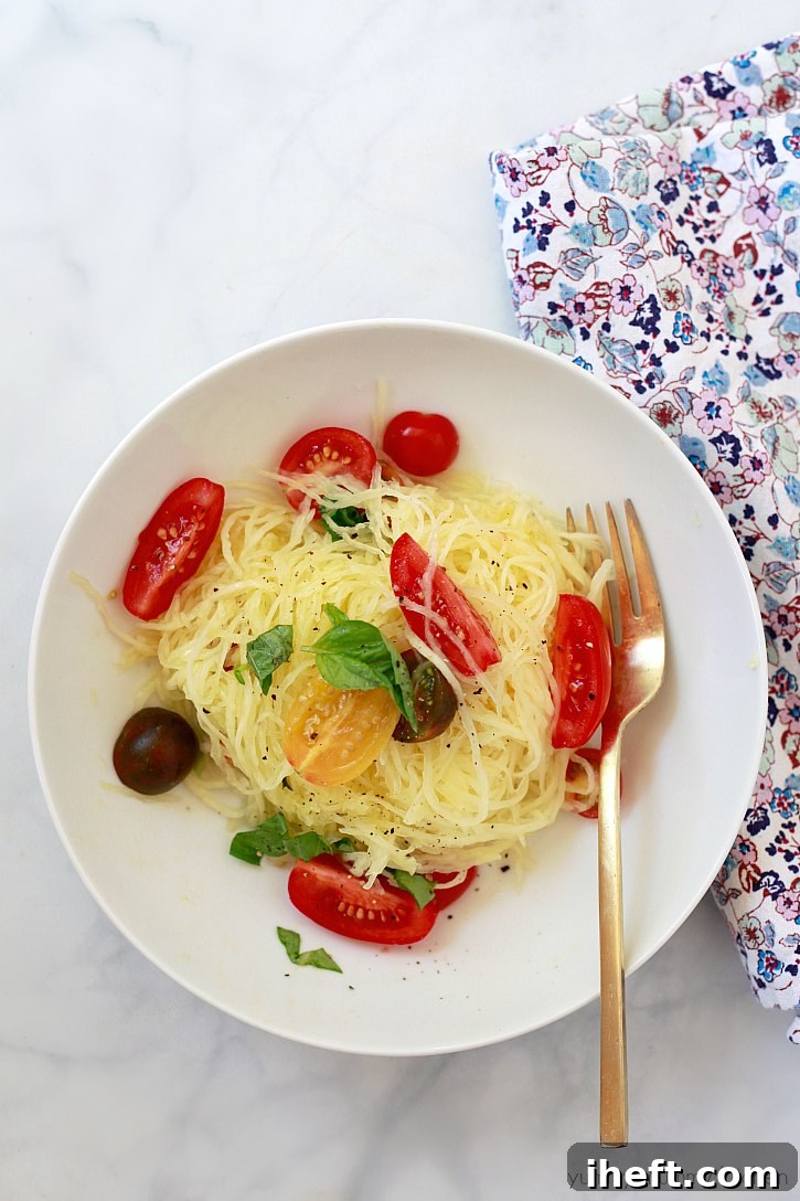 Boiled spaghetti squash noodles, elegantly tossed with fresh olive oil, vibrant mini tomatoes, and fragrant basil, creating a light and flavorful dish.
