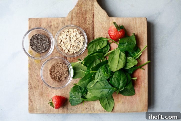 Small bowls of chia seeds, flax meal, oats, and baby spinach on a cutting board. 