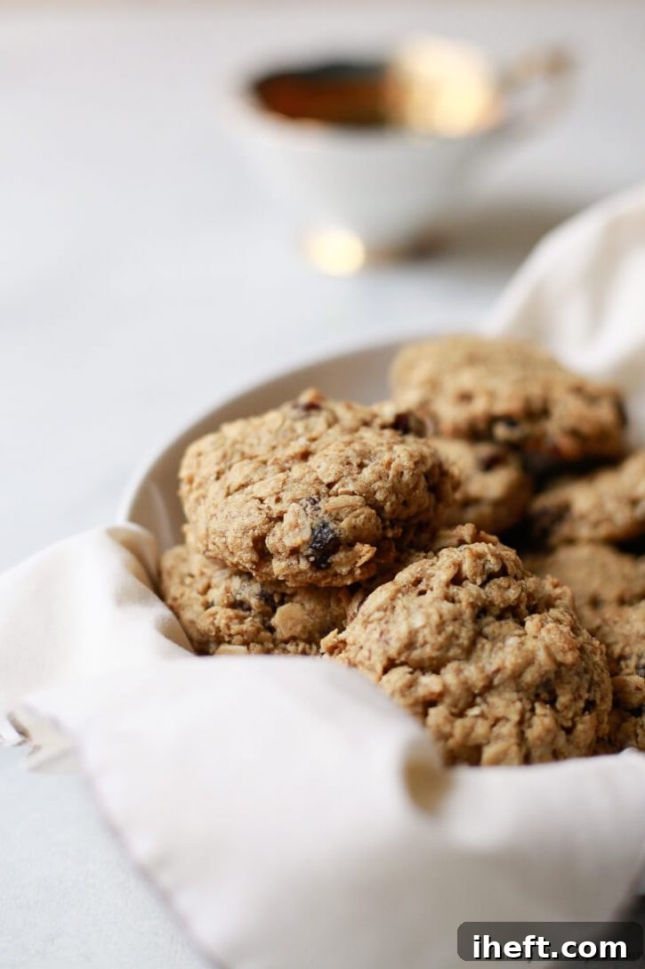 Close up photo of classic chewy oatmeal raisin cookies in a white bowl. These delicious oatmeal raisin cookies are vegan and gluten free. 