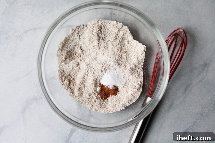 Oat flour, baking soda, and cinnamon in a bowl to make gluten free oatmeal raisin cookies. 