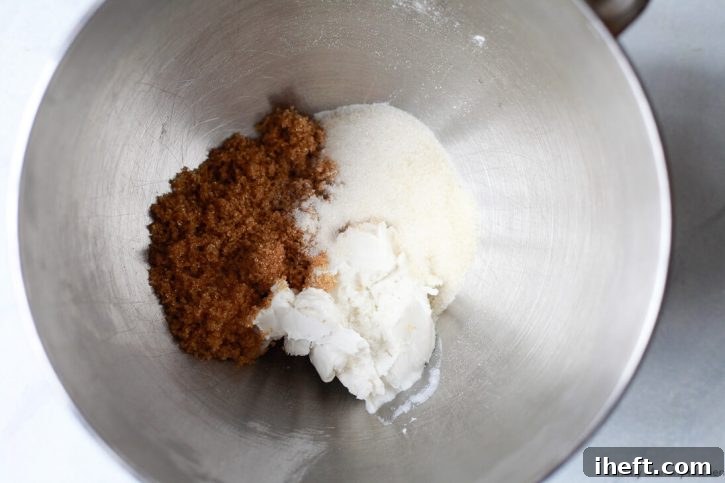 Brown and white sugars with vegan butter in the bowl of a KitchenAid mixer. 