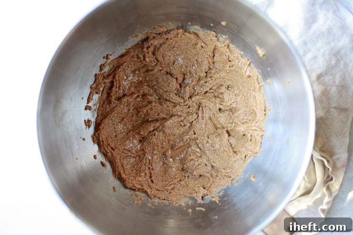 Close-up of whipped peanut butter and coconut sugar mixture in the bottom of an electric mixer bowl, creating a smooth and airy base for the snack bars.