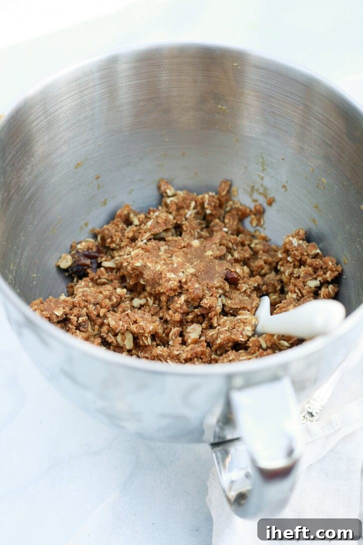 The rich, textured dough for peanut butter snack squares resting in a silver mixing bowl, ready for the final additions before baking.