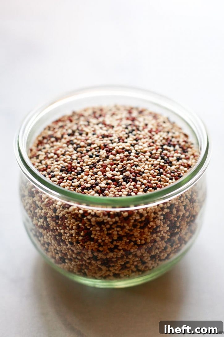 A glass jar filled with uncooked dry tricolor quinoa. 