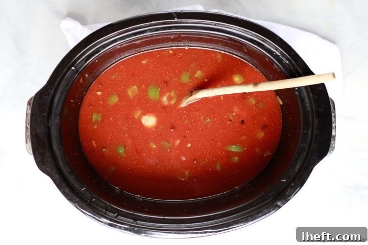 Vegetable broth is added to the vegan lentil sloppy joes ingredients and ready to cook in the slow cooker. 
