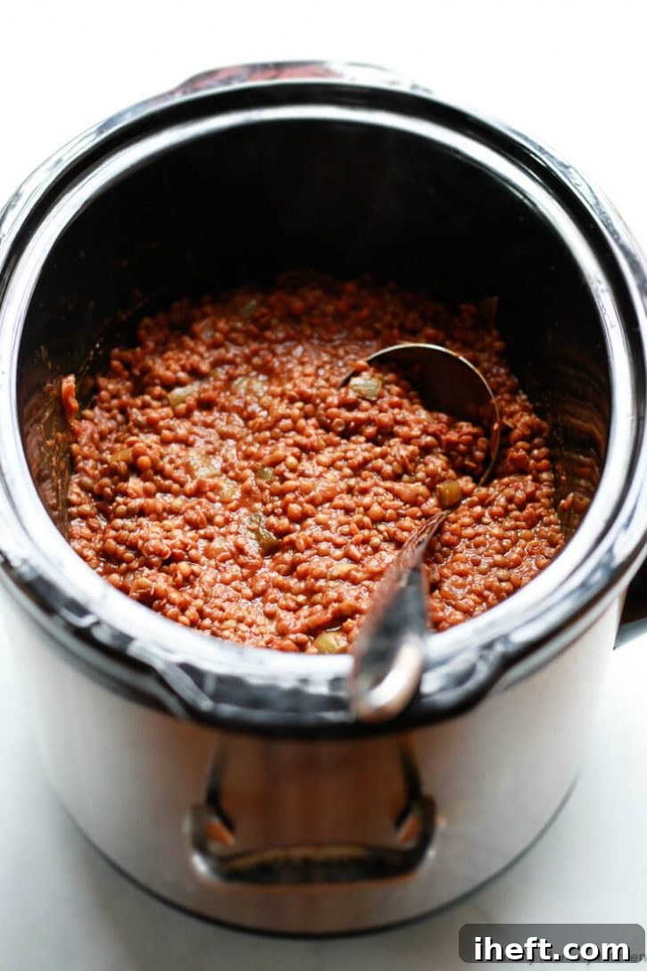 Vegan lentil sloppy joes in the slow cooker with a ladle. 