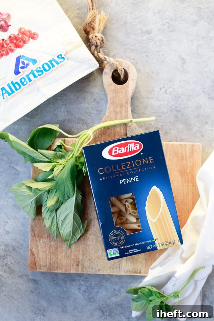 Barilla Collezione penne pasta on a cutting board with basil. 