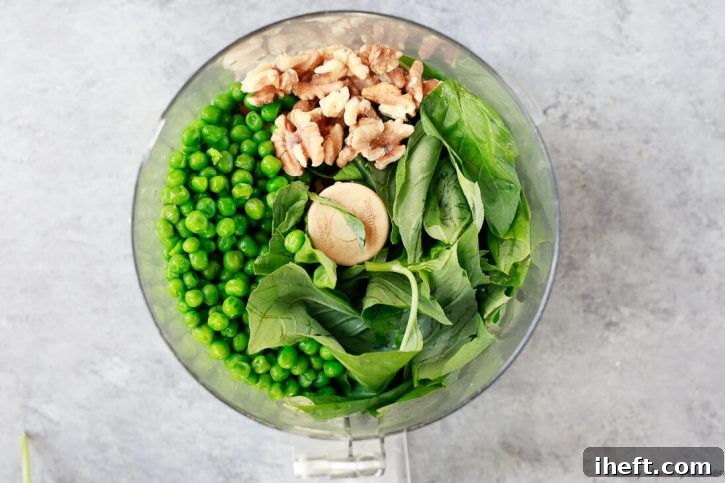 Ingredients for pea pesto in a food processor include walnuts, basil, and peas. 