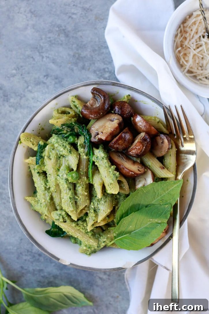 Pea pesto penne pasta in a white bowl with mushrooms and fresh basil. This vegan pesto pasta is a delicious lunch or dinner recipe. 