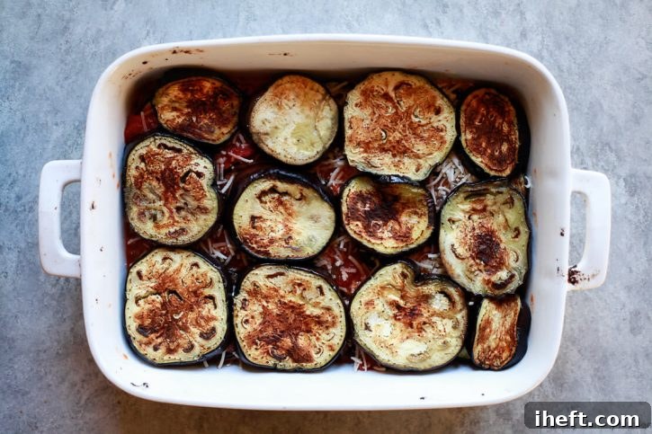 The top layer of eggplant is assembled on top of tomato sauce and vegan parmesan for a healthy vegan eggplant parmesan recipe. 