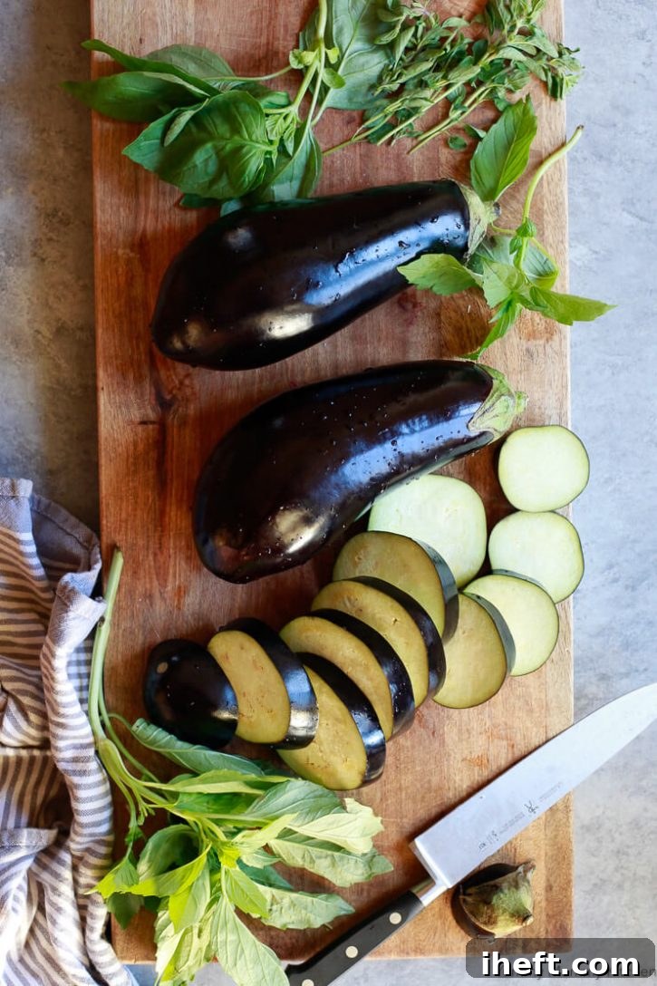 Eggplants are sliced on a wooden cutting board with basil. 