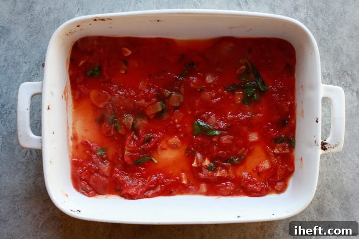 Pomodoro sauce sits in the bottom of a casserole dish to start layering eggplant parmesan. 