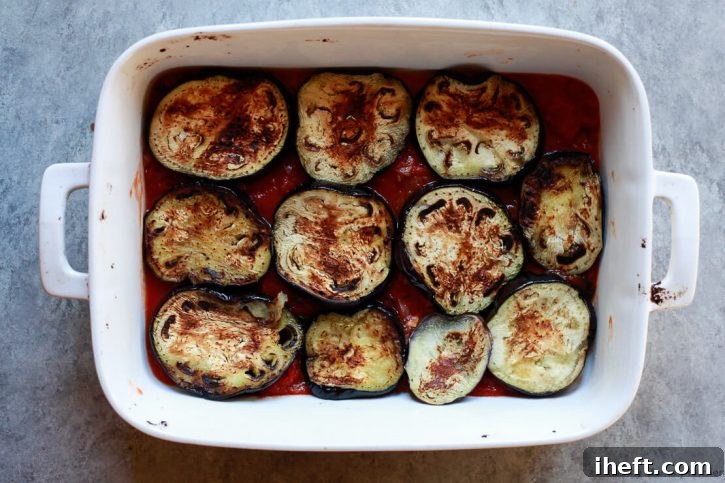 Eggplant slices on top of pomodoro sauce in a baking dish. 