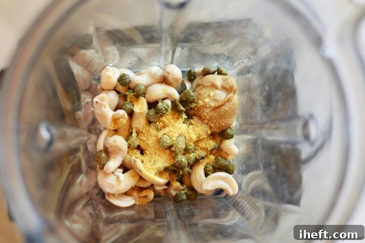 All the whole ingredients for a luscious Vegan Caesar Salad Dressing are carefully placed inside a powerful Vitamix blender, poised and ready to be transformed into a creamy, flavorful concoction. This vibrant image captures the moment before blending, highlighting the fresh, wholesome components.
