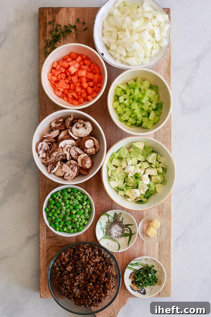 A colorful array of fresh vegetables including carrots, celery, mushrooms, and peas, alongside black lentils, prepared for a delicious vegan lentil shepherd's pie recipe.