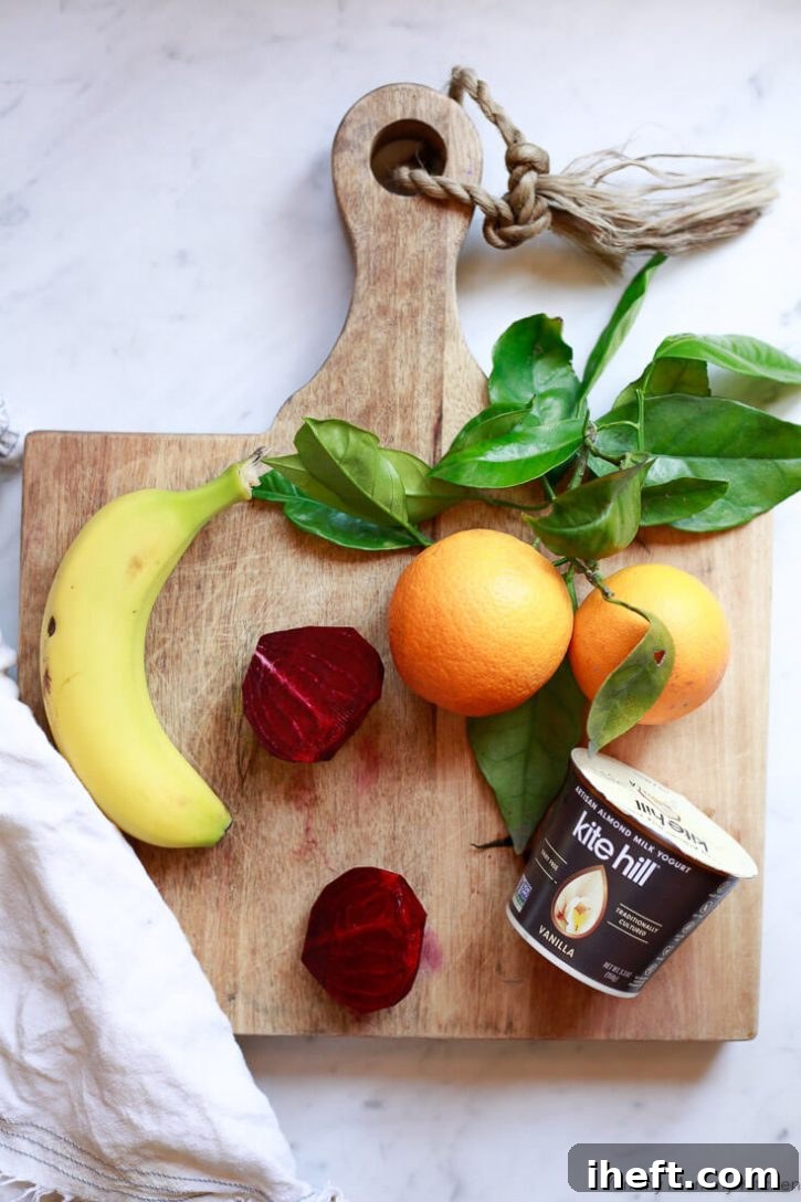 A raw beet, banana, oranges, vegan yogurt sit on a cutting board. 