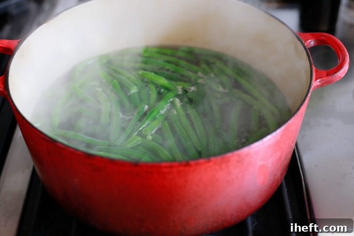 Green beans boil in a large red pot. 