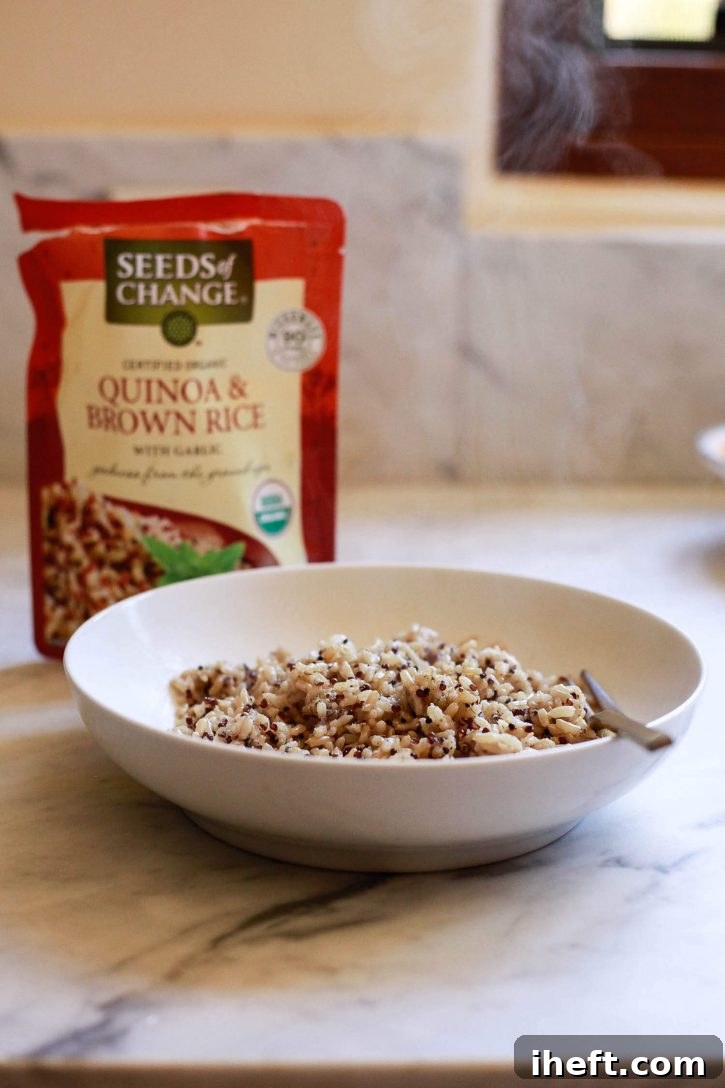A steaming bowl of freshly cooked quinoa and brown rice releases fragrant wisps of steam in a bright, modern white kitchen, indicating its warmth and readiness as the perfect base for a healthy meal.
