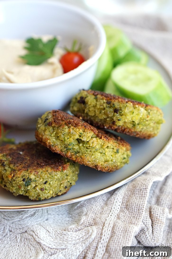 A close-up image of three falafel on a plate with hummus. 