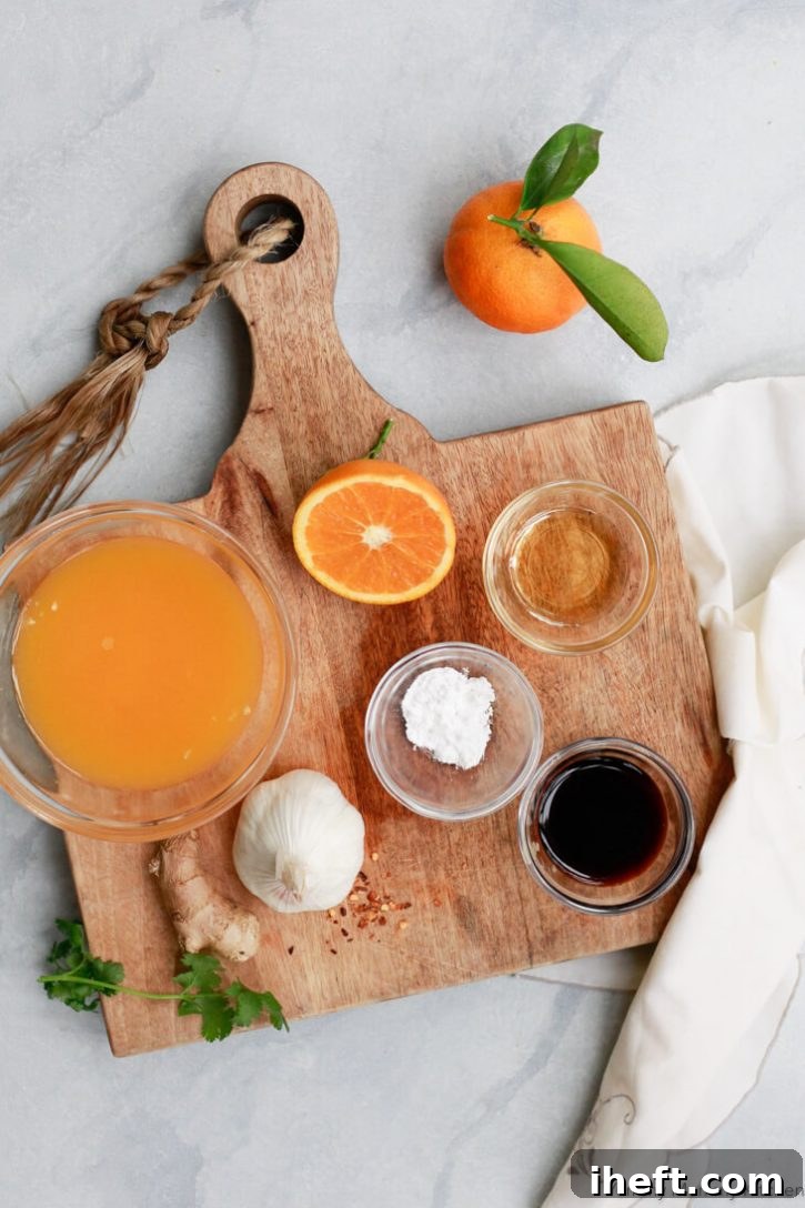 The ingredients for orange stir fry sauce sit on a wooden cutting board on a white countertop.