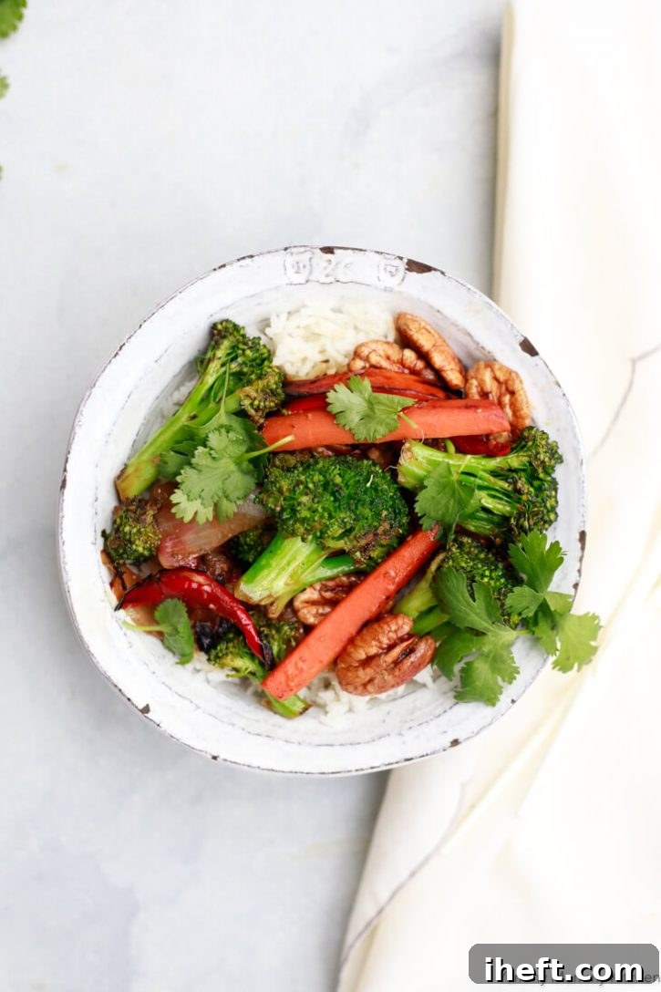 A white ceramic bowl filled with white rice and stir fry vegetables like broccoli and carrots.