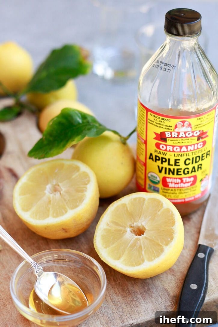 Bragg's apple cider vinegar, fresh lemons, and honey on a cutting board to make natural detox drinks. 