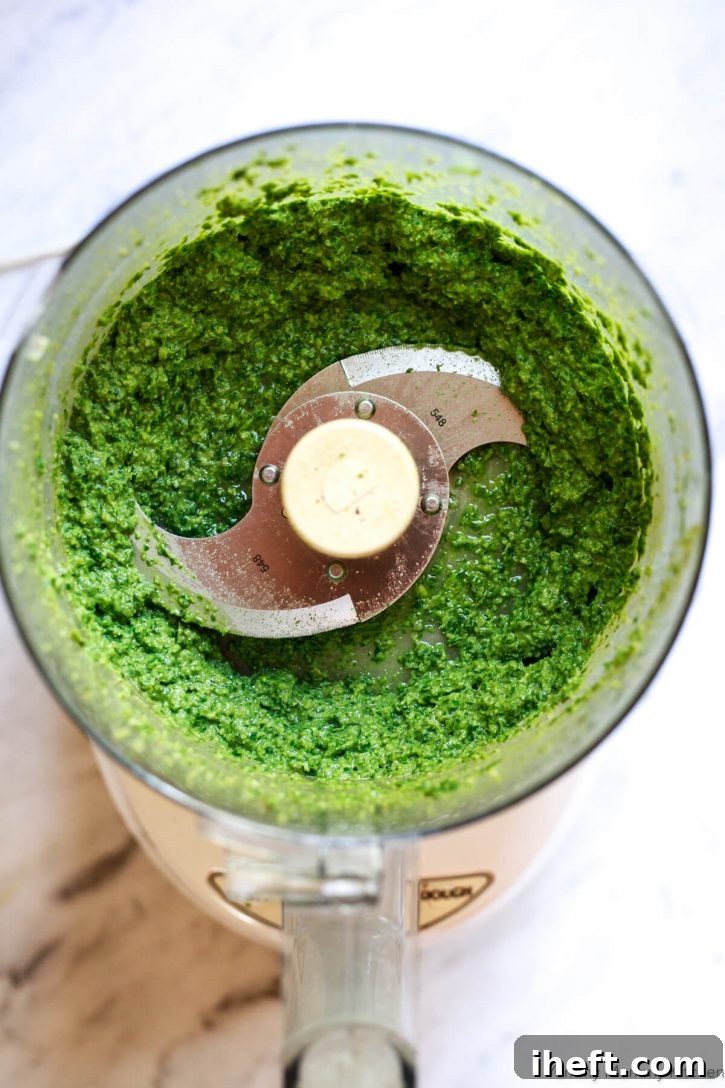 A beautiful bright green homemade vegan basil pesto in a food processor. 