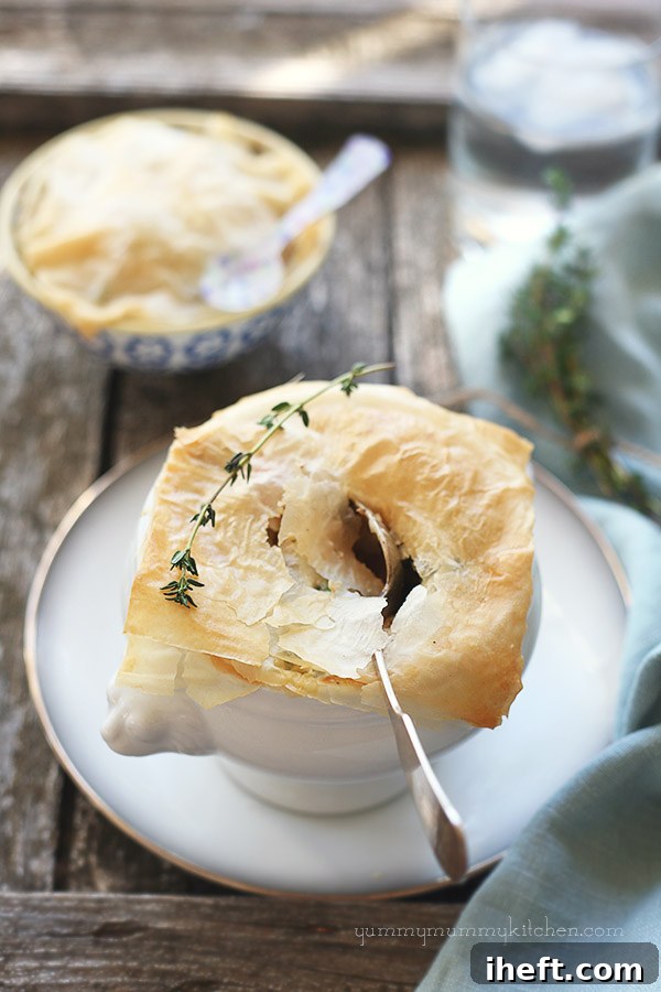 Vegetarian Pot Pie with a golden, flaky phyllo crust, baked in a small ceramic bowl and garnished with fresh herbs.