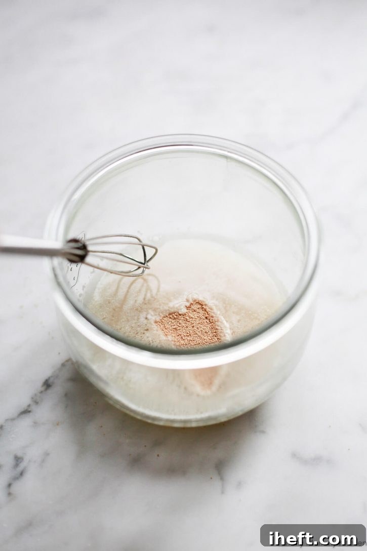 Active dry yeast in a small bowl with water and a small whisk. Yeast is proofed and activated for making homemade pizza dough. 