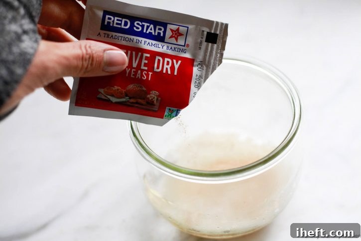 A packet of Red Star active dry yeast pouring into a bowl of water. 