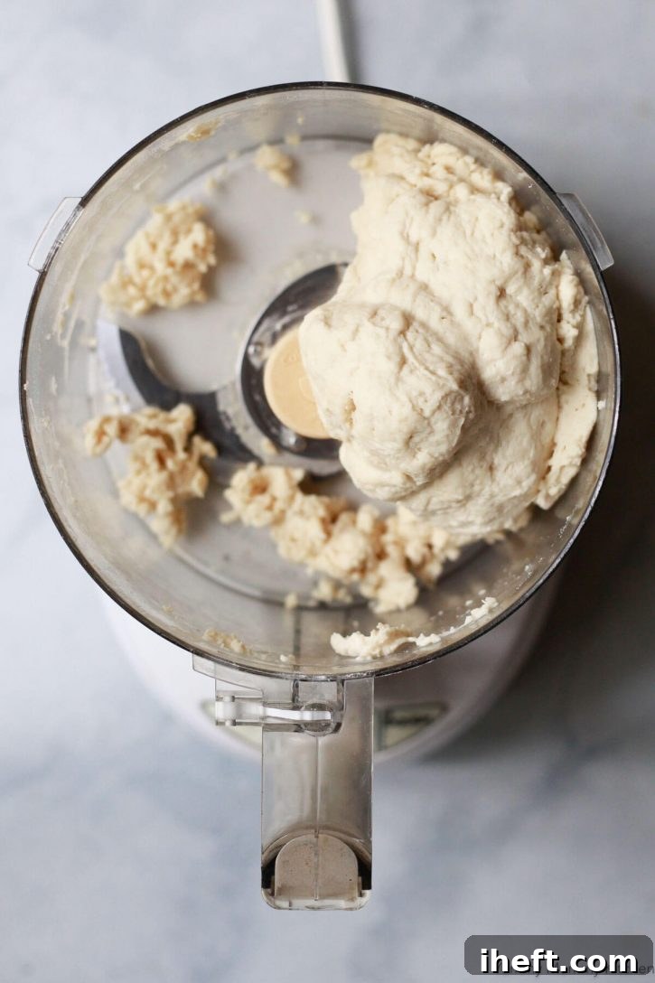 Pizza dough comes together in the bowl of a food processor. 
