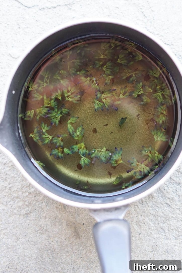 Lavender simple syrup with lavender flowers in a small black saucepan.