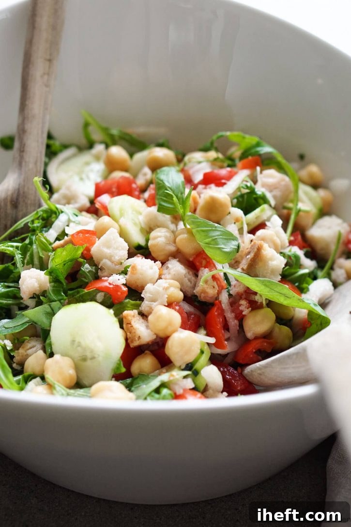 A bowl of panzanella salad with chickpeas and arugula. This photo was taken in Tuscany while making panzanella bread and tomato salad. 