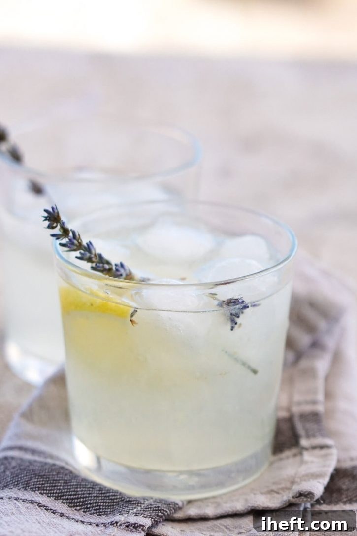 A glass of cold lavender lemonade with ice and fresh lavender. 