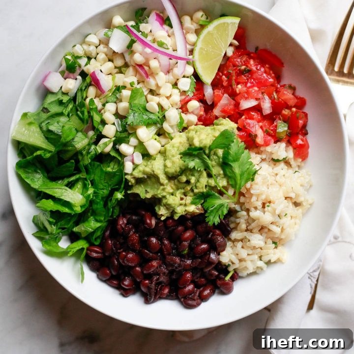 A vegetarian Chipotle inspired burrito bowl with brown rice, black beans, salsa, corn salsa, romaine, and guacamole.