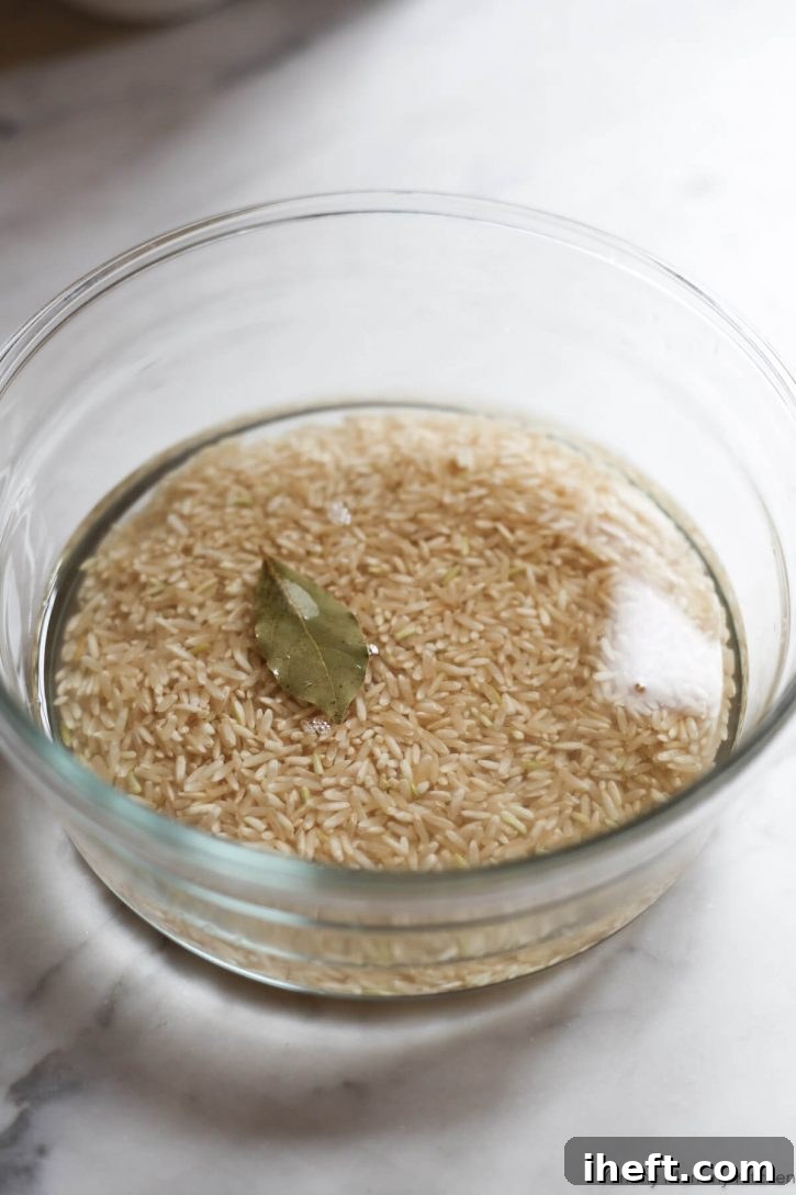 A glass dish of brown rice, bay, leaf, water and salt for pot in pot cooking with the Instant Pot. 
