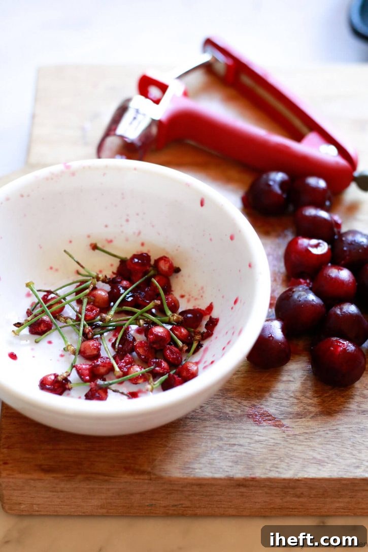 Fresh cherries are pitted using a red cherry pitter. 