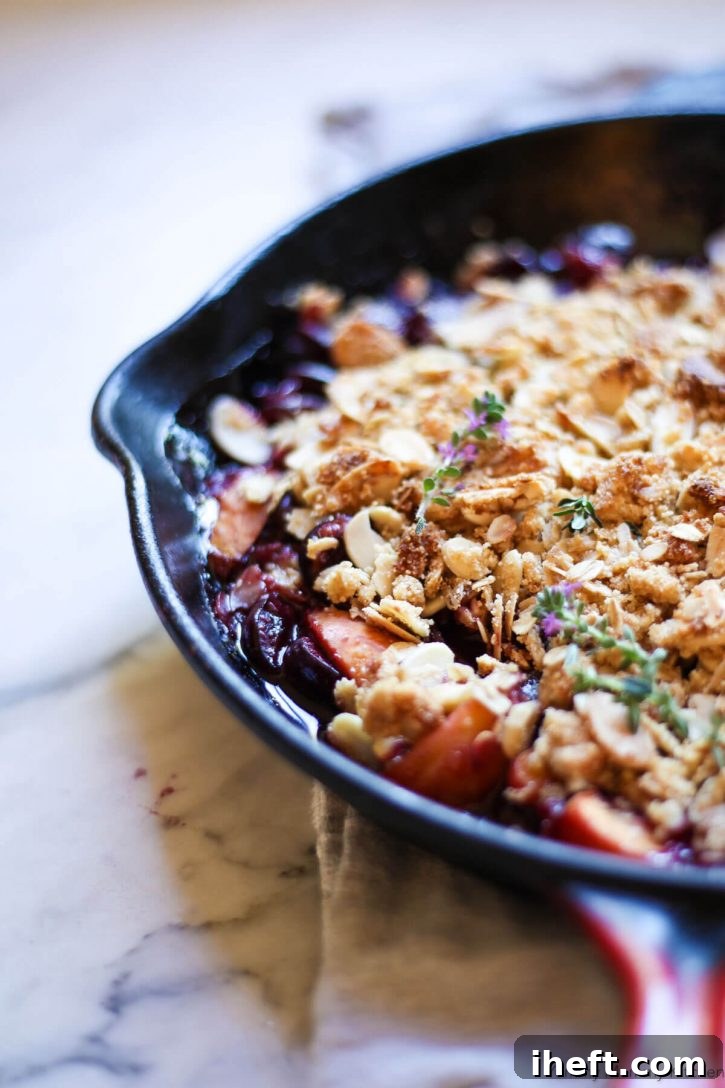 Bubbly fresh cherry and apricot crisp in a skillet topped with golden almond crisp topping. 