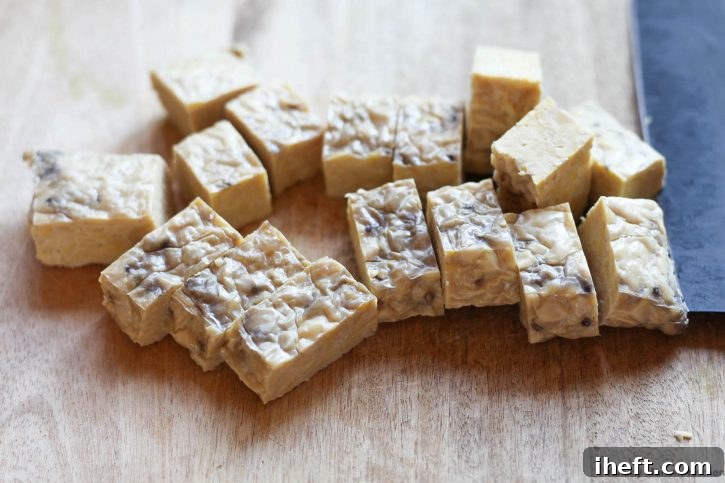 Cubes of Trader Joe's organic tempeh on a cutting board before using in recipes.
