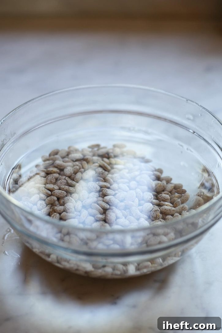 A glass bowl of water and pinto beans soaking. 