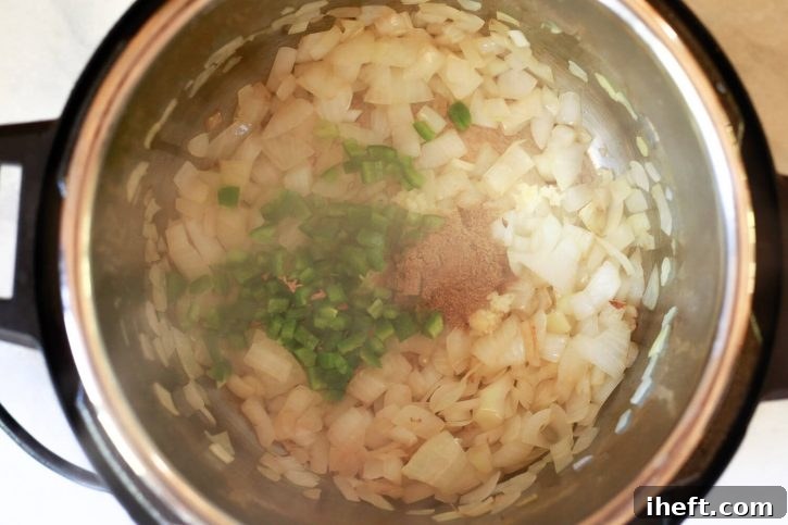 Onions, jalapeno, cumin, and garlic saute in a pot. 