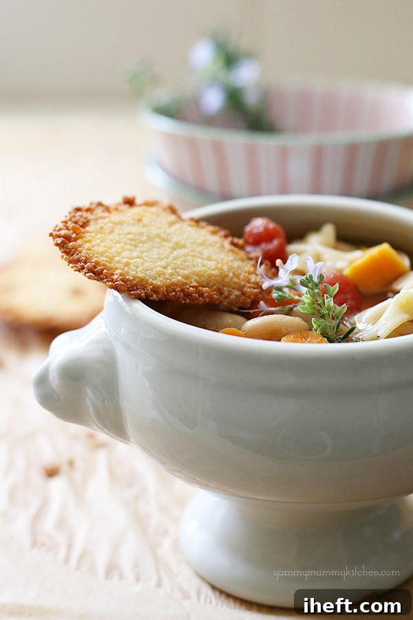 A white lion ceramic bowl filled with vegetarian pasta e fagioli soup topped with a parmesan crisp. 