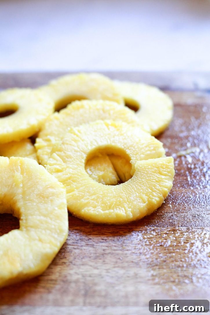 Freshly cut pineapple rings on a cutting board. Shows uniform rings, some with the core removed.