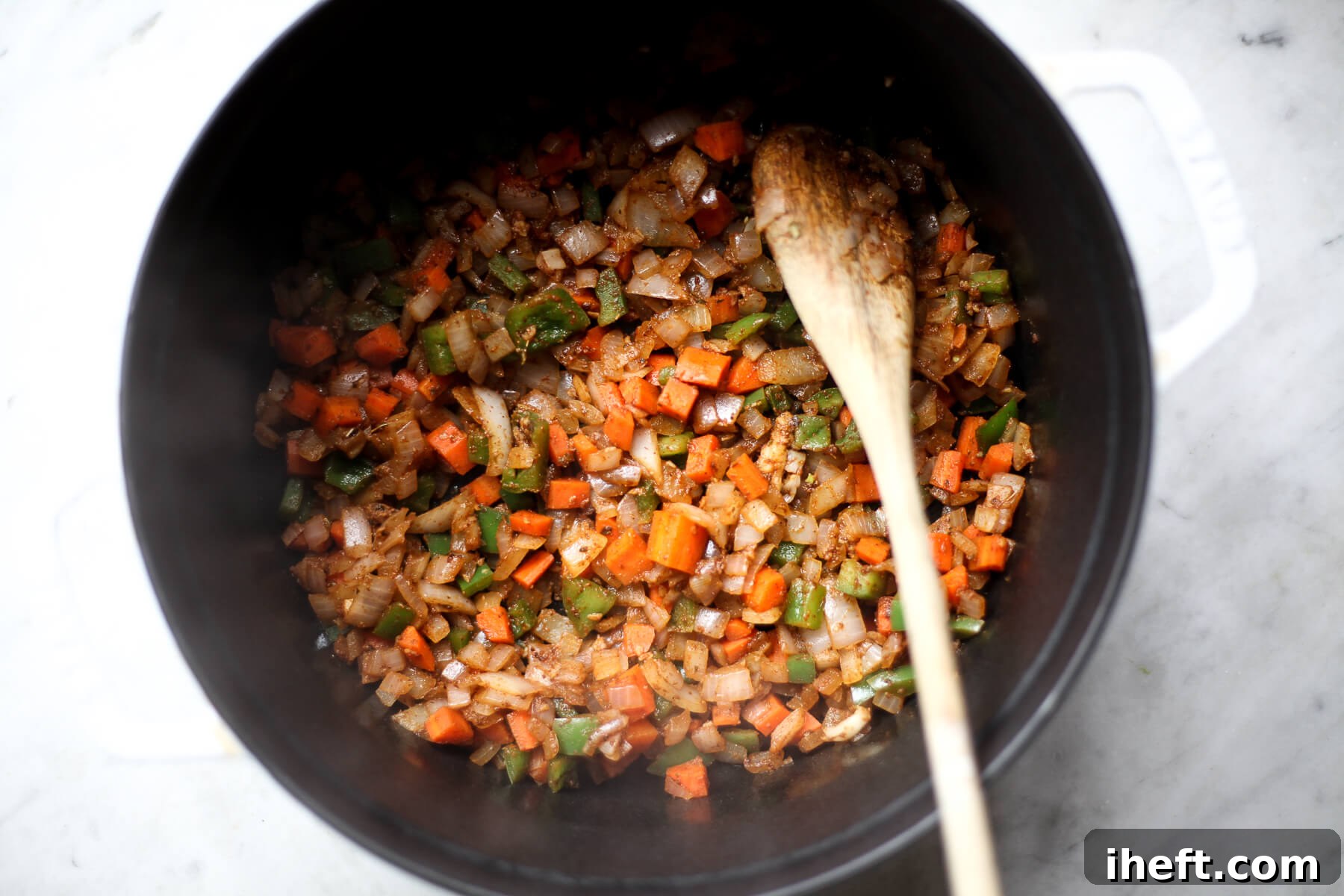 Spices and garlic saute with onion, carrot, and bell pepper to start making vegan chili.