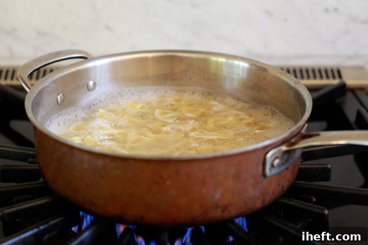 Bow tie pasta simmers gently on the stove in a large pot of salted water.