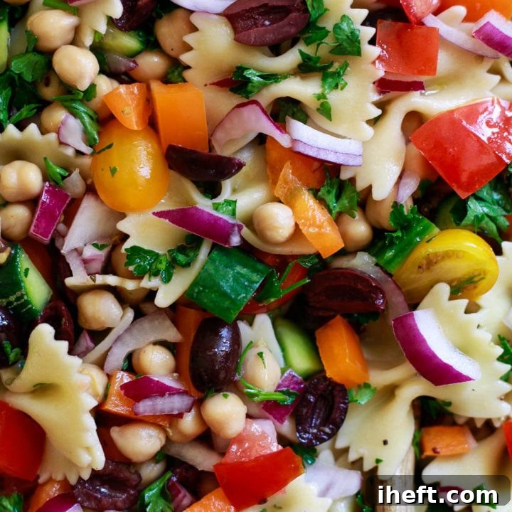 Vegan pasta salad with bow tie pasta and healthy Greek flavors in a rustic bowl.