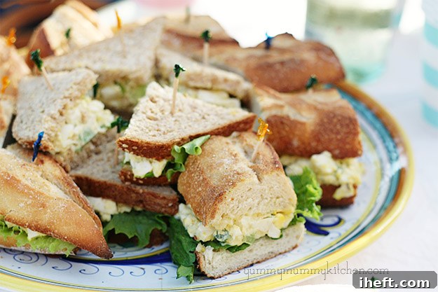 A close-up of classic egg salad sandwiches, some on baguette and some on soft bread.