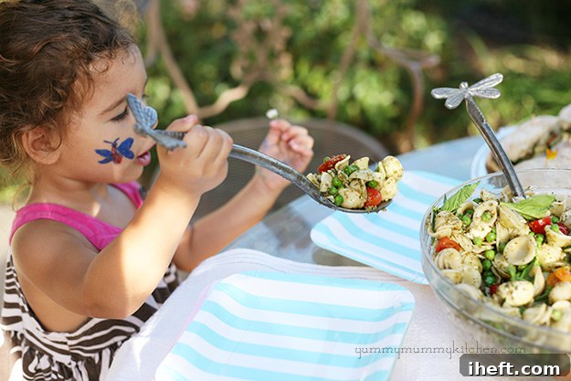 Pesto pasta salad with peas, tomatoes, and mozzarella in a serving bowl.