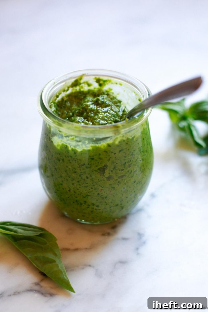 A small Weck jar elegantly filled with homemade vegan basil and walnut pesto, showcasing its rich green color and fresh texture on a countertop.